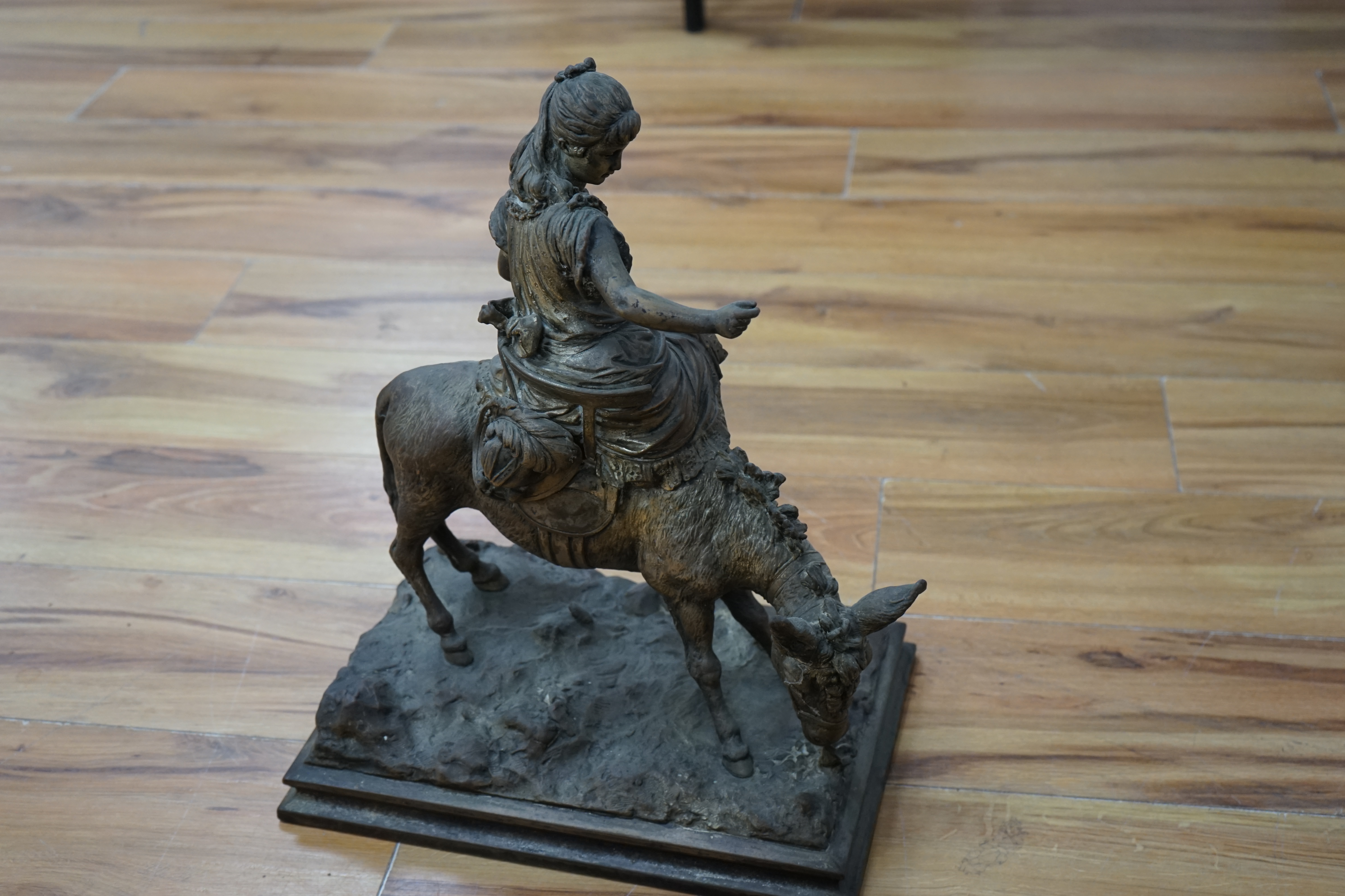 A silvered resin figure of a girl on a donkey, 45cm high. Condition - poor